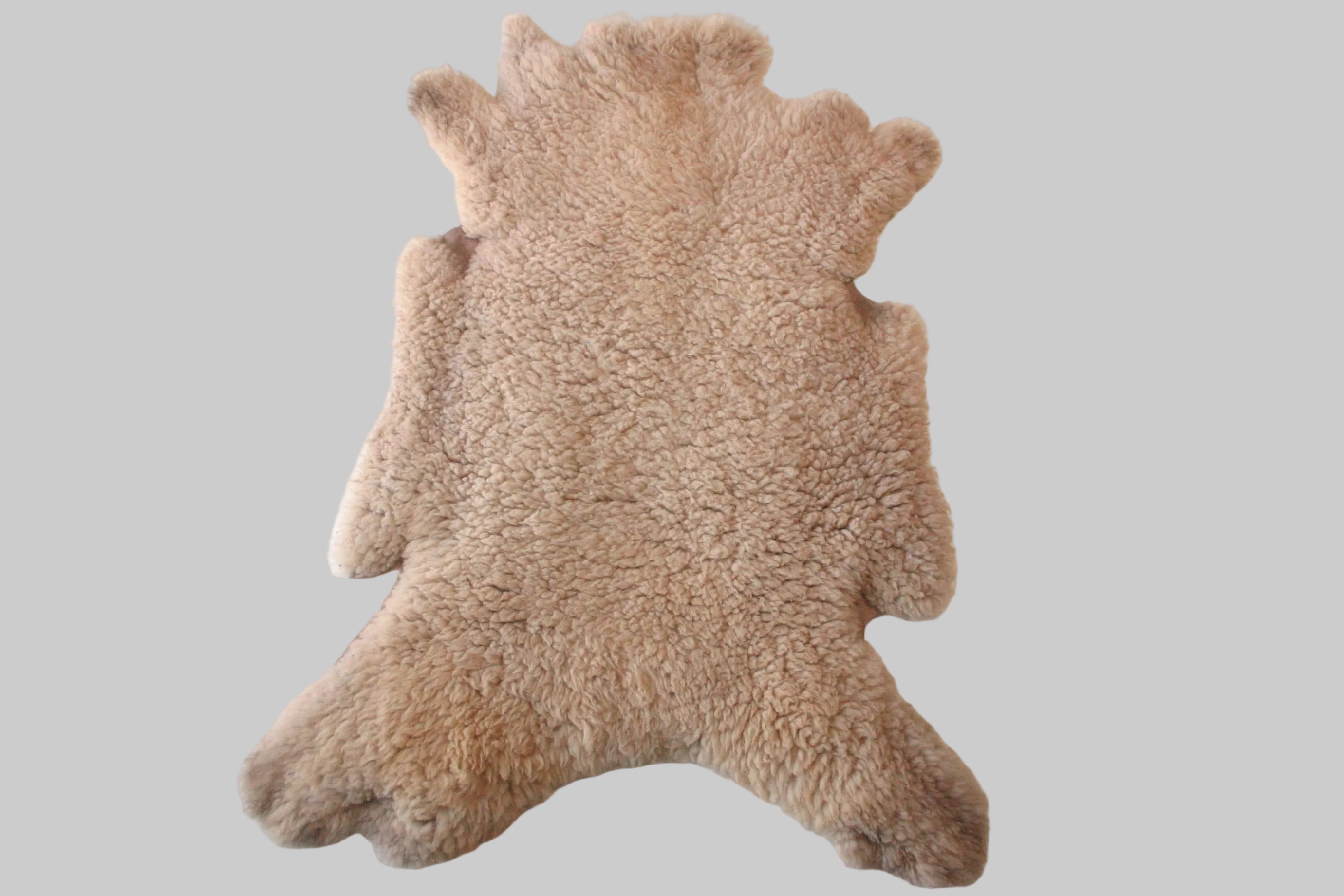 Beige sheepskin rug on a white floor